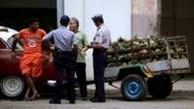 La policía registra el cargamento de un vendedor de piñas / Foto: Desmond Boylan (Reuters)